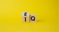 IQ or EQ symbol. Turned cube with words IQ, intelligence quotient to EQ, emotional quotient. Beautiful yellow background.