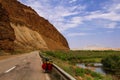 Bike to travel in the road of Iran with a valley and green grass on the side. Orange rocks and desert mountains