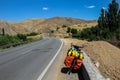 Bike to travel in the road of Iran with a valley and green grass on the side. Orange rocks and desert mountains