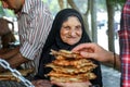 Iran, Persia, Shiraz - September 2016: an elderly local woman buying bread in a street bench