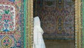 Woman leaning to a door with colored tiles Nasir al-Mulk Mosque, Shiraz, Iran
