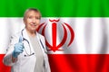 Irani smiling mature doctor woman holding stethoscope on flag of Irani background Royalty Free Stock Photo