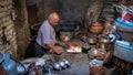 Iranian man working with copper cookware in his copper store, Yazd, Iran