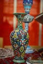 Iranian porcelain vase with national handmade ornament.On a silk handkerchief against a high vase and an orange tulle curtain. Royalty Free Stock Photo