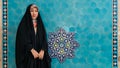 Iranian woman in hijab black dress standing infront of a tile in Jameh Mosque of Yazd, Iran