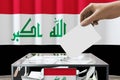 Iraq flag, hand dropping ballot card into a box