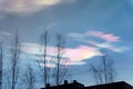 Iridescent clouds (Rainbow clouds) on the sky in the evening with tree and house silhouettes Royalty Free Stock Photo