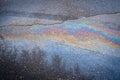 Iridescent spot of gasoline on the road with tire tracks.