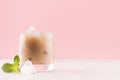 Irish coffee cocktail with cream and ice cube, green mint in misted glass on white wood board in light pink color background. Royalty Free Stock Photo