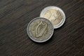 Used coins on a dark wooden table. Irish 2 euro coins