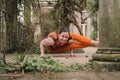 Woman new yoga teacher doing an eight-angle pose wearing orange sportswear in the terrace of a landscaped garden in Royalty Free Stock Photo