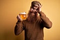 Irish redhead man with beard drinking a glass of refreshing beer over yellow background with happy face smiling doing ok sign with Royalty Free Stock Photo