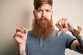 Irish redhead man with beard holding dental invisible aligner for tooth correction with angry face, negative sign showing dislike Royalty Free Stock Photo