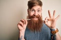 Irish redhead man with beard holding dental invisible aligner for tooth correction doing ok sign with fingers, excellent symbol Royalty Free Stock Photo