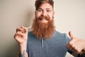 Irish redhead man with beard holding dental invisible aligner for tooth correction happy with big smile doing ok sign, thumb up Royalty Free Stock Photo