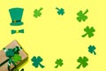 Framed green hat and leaves of clover, shamrock, trefoil on yellow background