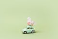 Irkutsk, Russia - january 17, 2021: Light green retro toy car carries easter egg. Minimal easter concept