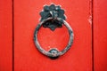 Iron antique ring handle on a red wooden door.