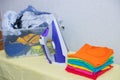 Iron and baby clothes. Colored clothes on an ironing board. Bright t-shirts. Ironed and non-ironed colored children`s underwear o Royalty Free Stock Photo