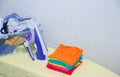 Iron and baby clothes. Colored clothes on an ironing board. Bright t-shirts. Ironed and non-ironed colored children`s underwear o Royalty Free Stock Photo