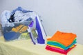 Iron and baby clothes. Colored clothes on an ironing board. Bright t-shirts. Ironed and non-ironed colored children`s underwear o Royalty Free Stock Photo