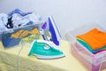 Iron and baby clothes. Colored clothes on an ironing board. Bright t-shirts. Ironed and non-ironed colored children`s underwear o Royalty Free Stock Photo