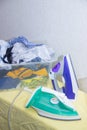 Iron and baby clothes. Colored clothes on an ironing board. Bright t-shirts. Ironed and non-ironed colored children`s underwear o Royalty Free Stock Photo