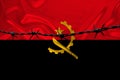 Iron barbed wire against the background of the national silk flag of the state of Angola, concept of imprisonment for offenders,