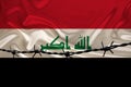 Iron barbed wire against the background of the national silk flag of the state of Iraq, the concept of imprisonment for offenders