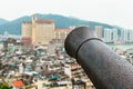 Iron barrel of ancient cannon on top platform of The Mount Fortress Museum of History aimed at Macau cityscape