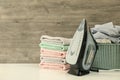 Iron, basket with laundry and pile of towel against wooden background Royalty Free Stock Photo