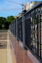 Iron black forged fence along a walkway on the city promenade in the background of a construction crane Royalty Free Stock Photo