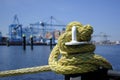 A iron bollard with a tied rope on a quay in the Port of Rotterdam in the Netherlands. In the background, slightly out of focus, Royalty Free Stock Photo