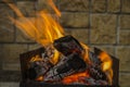 Iron brazier with burning coals and flame on stone wall background Royalty Free Stock Photo