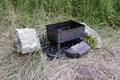 Iron brazier with charcoals and stones lying around in a barbecue place.