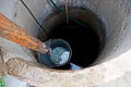 Iron bucket with water at the depth of a round well Royalty Free Stock Photo