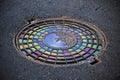 Iron cast manholes in a asphalt paving with colored oil Royalty Free Stock Photo