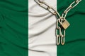 Iron chain and lock on the Nigeria silk national flag with beautiful folds, the concept of a ban on tourism, political repression