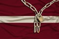 Iron chain and lock on the silk national flag of Latvia with beautiful folds, the concept of a ban on tourism, political