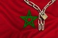 Iron chain and lock on the silk national flag of Morocco with beautiful folds, the concept of a ban on tourism, political