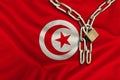 Iron chain and lock on the silk national flag of Tunisia with beautiful folds, the concept of a ban on tourism, political