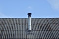 Iron chimney on the roof of the house with a visor