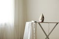 Iron and a clothes on an ironing board on a colored background. Royalty Free Stock Photo