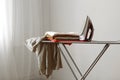 Iron and a clothes on an ironing board on a colored background. Royalty Free Stock Photo