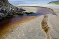 Iron coloured stream flowing into the sea. Royalty Free Stock Photo