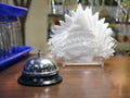 Iron desk bell and white paper napkins in plastic napkin stand on wooden reception desk of visitors