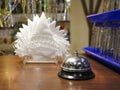 Iron desk bell and white paper napkins in plastic napkin stand on wooden reception desk of visitors