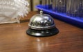 Iron desk bell and white paper napkins in plastic napkin stand on wooden reception desk of visitors