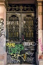 Iron door painted black with graffiti and wrought iron