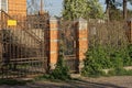 An iron door and part of a fence made of brown bricks and metal rods in a forged pattern Royalty Free Stock Photo